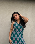 Woman wearing a green patterned dress against a plain background