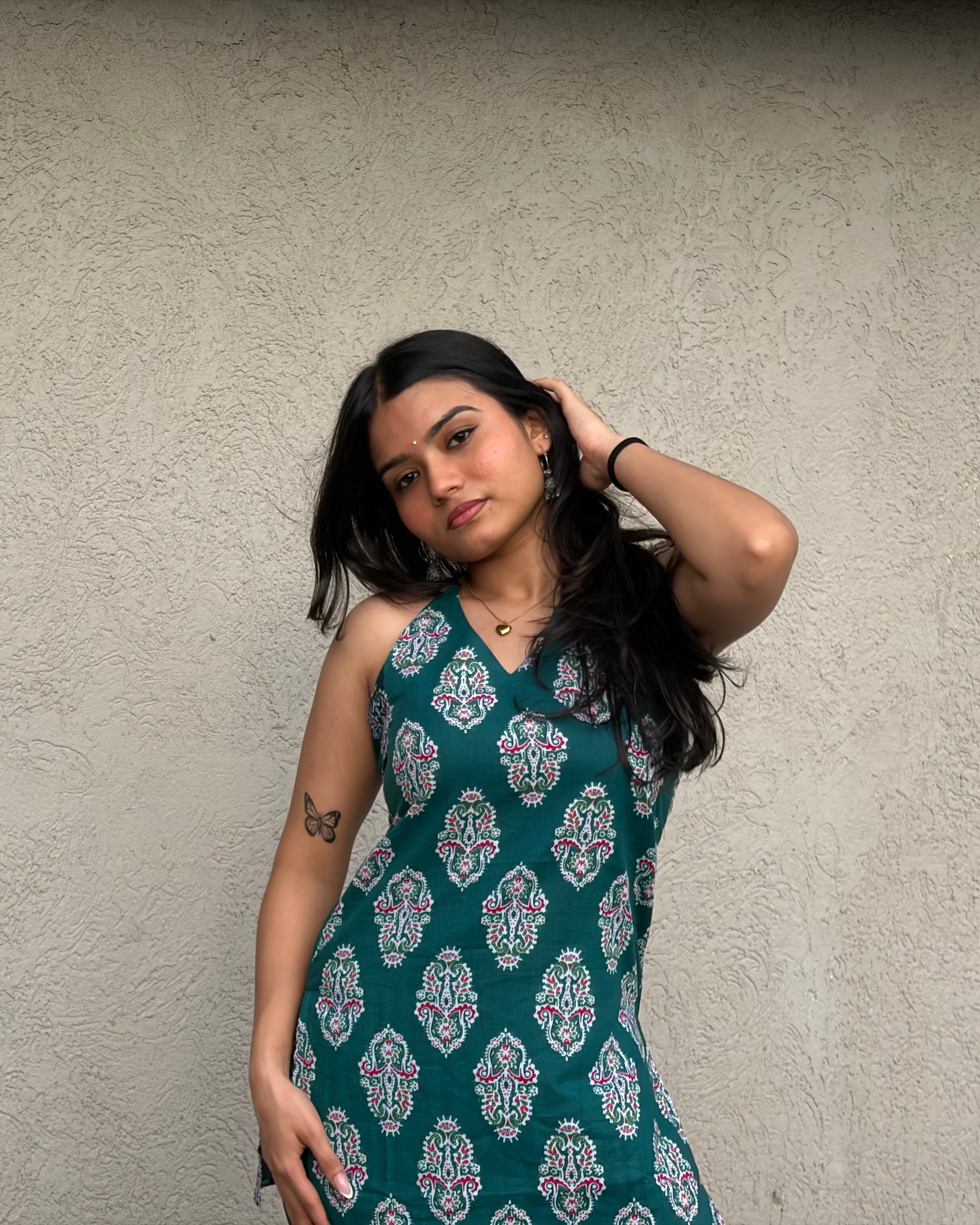 Woman wearing a green patterned dress against a plain background